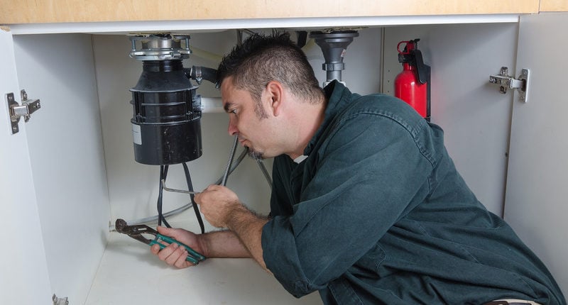 Plumber Fixing A Garbage Disposal