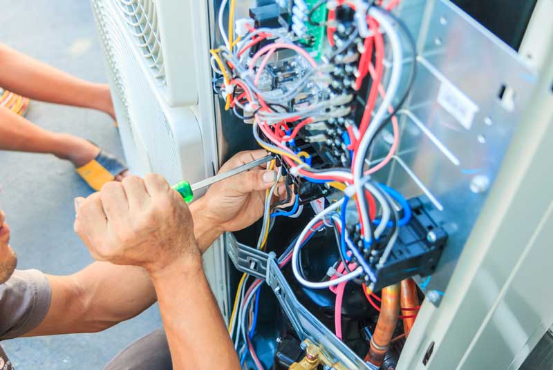 air conditioning tech working on the main board of an ac unit