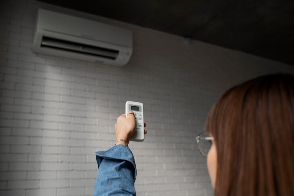 A woman turning on the AC with a remote.